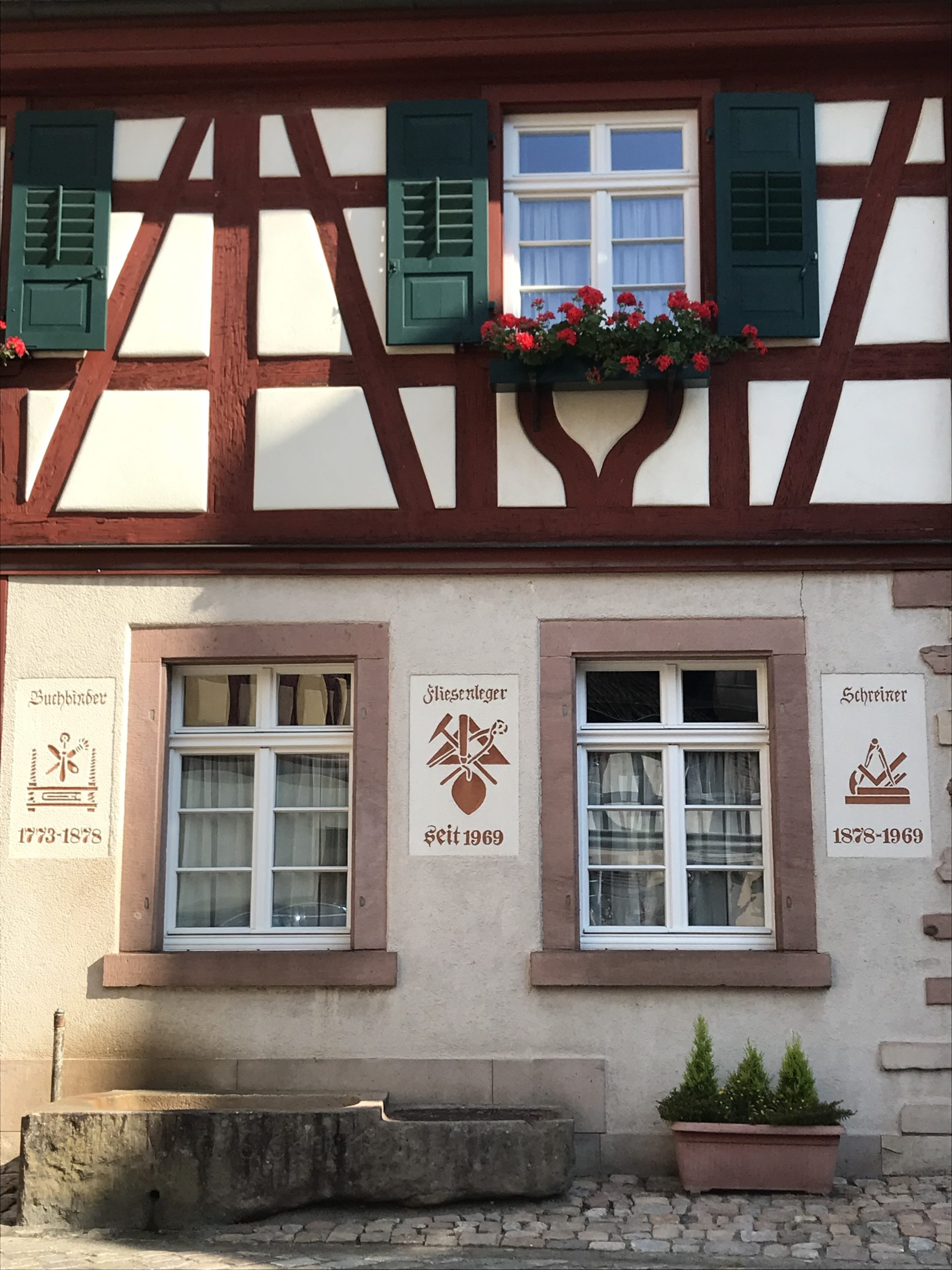 Ein altes Fachwerkhaus und Wappen der Gewerke an der Wand 