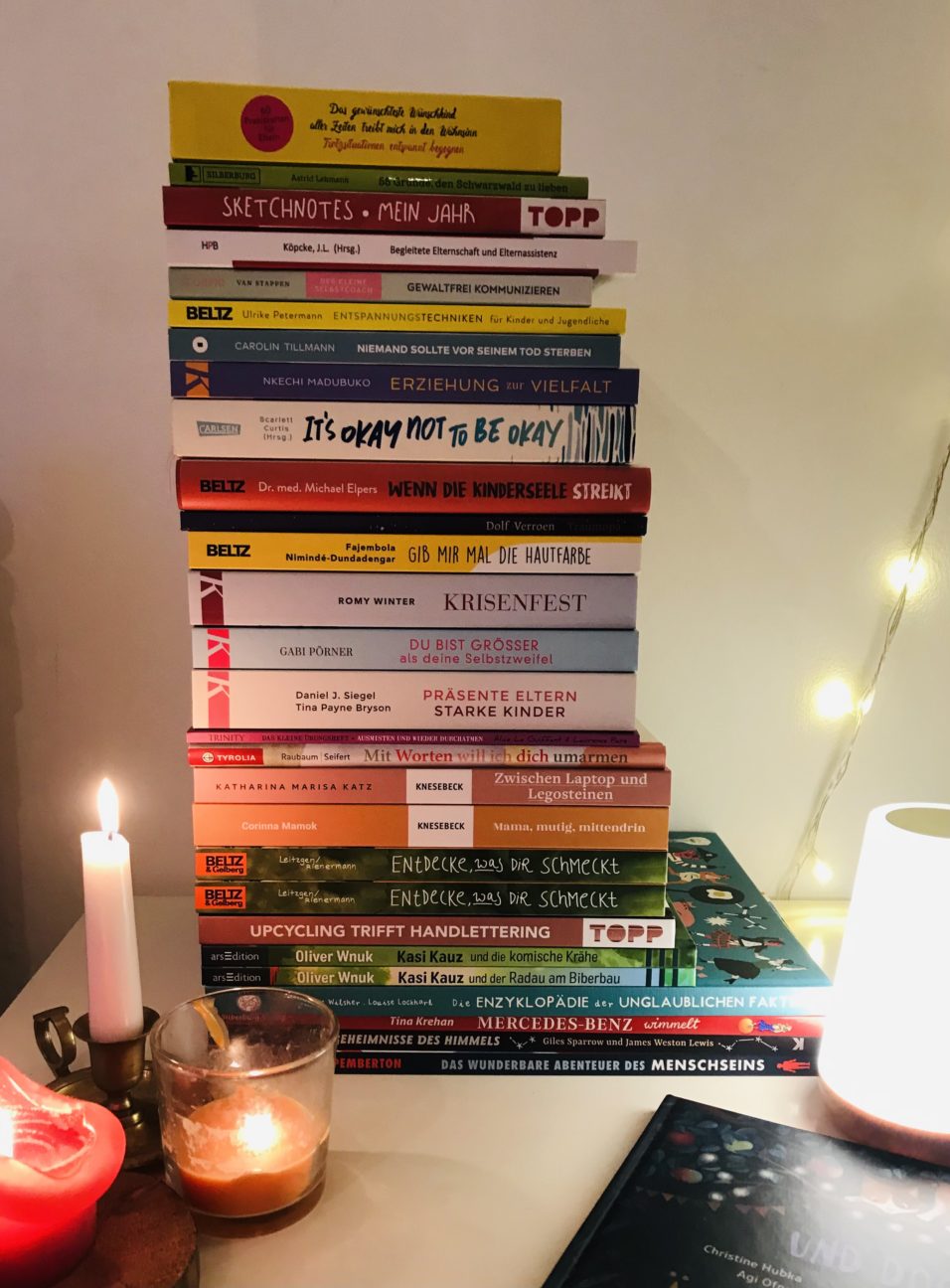 Ein Stapel voller Bücher mit Kerzen daneben