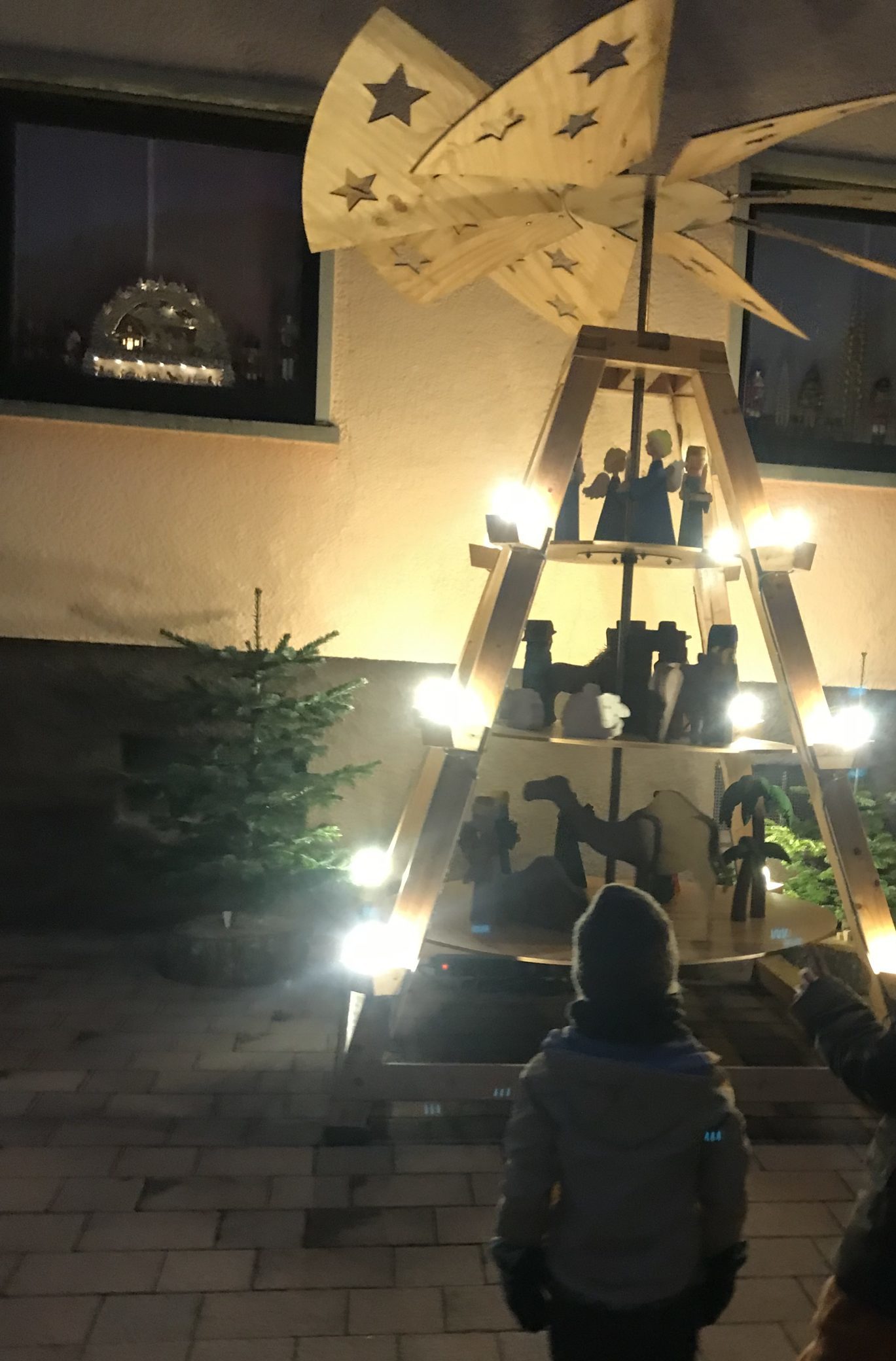 Die Kinder stehen vor einer großen Weihnachtspyramide die beleutete ist und sich dreht