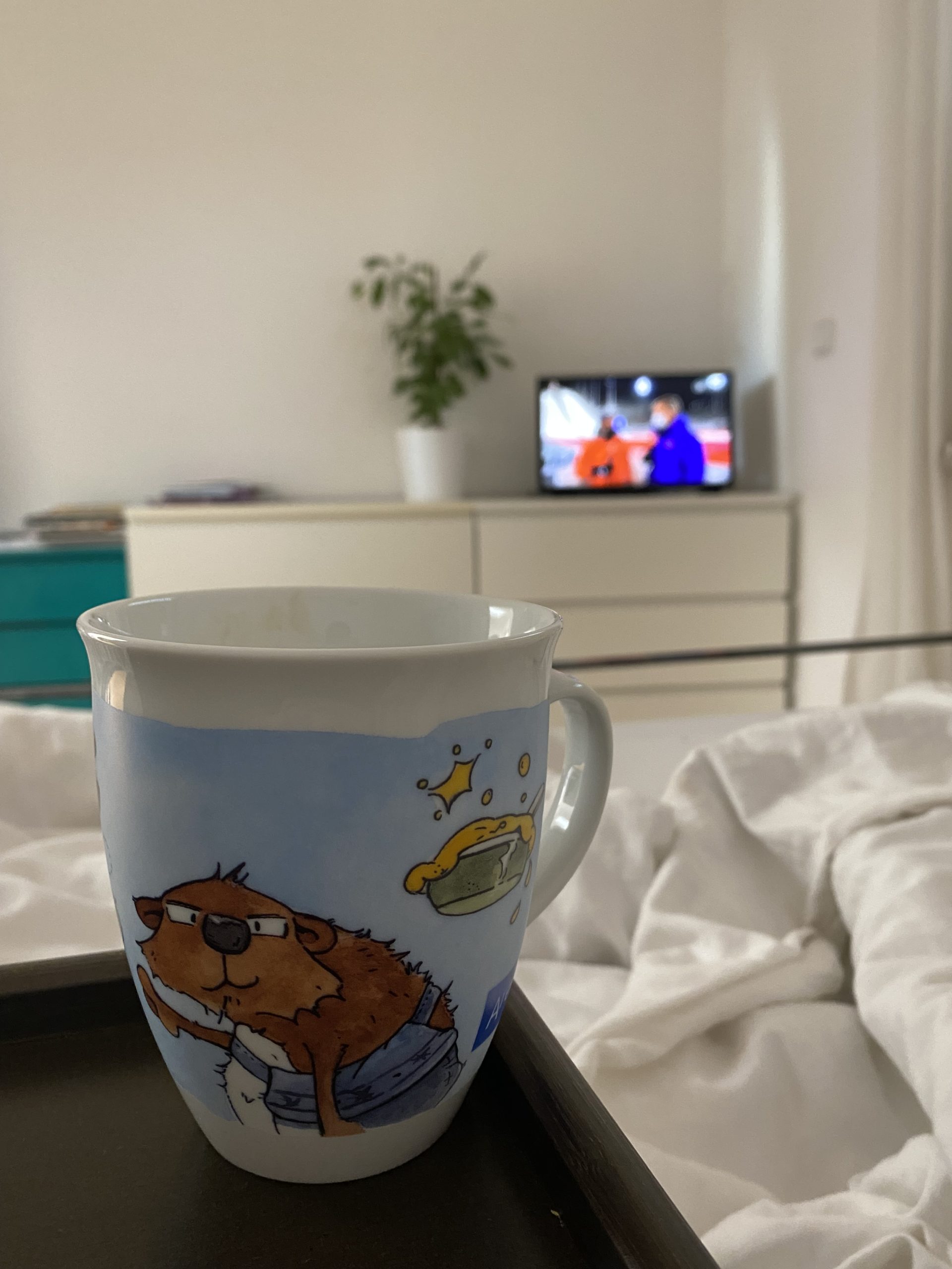 Ein Kaffee im Bett mit TV dahinter 