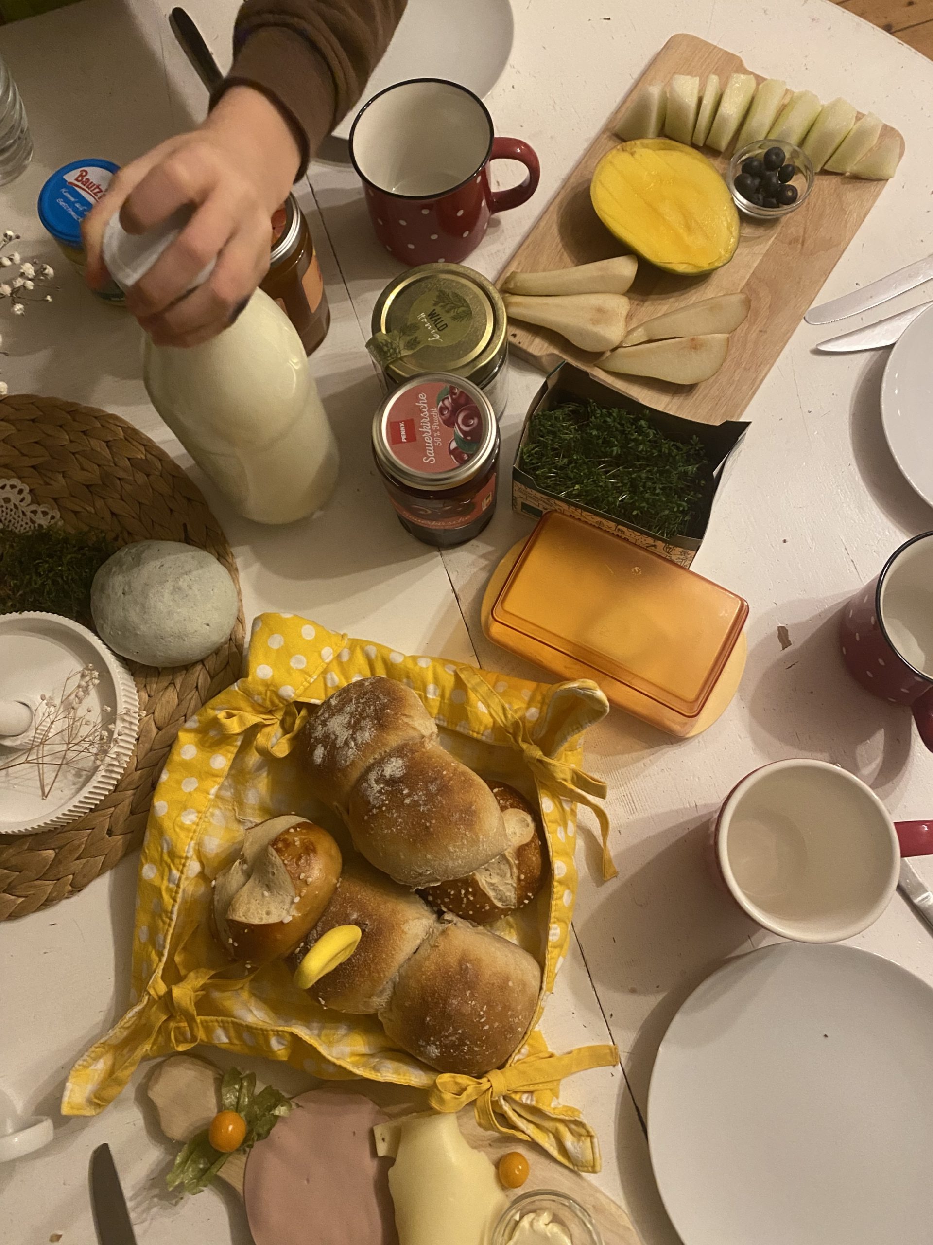 Frühstückstisch mit Brötchen, Kaffee, Milch, Butter und Marmelade 