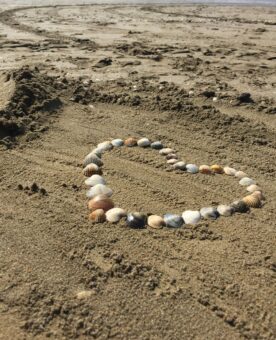 Ein Herz aus Muscheln im Sand
