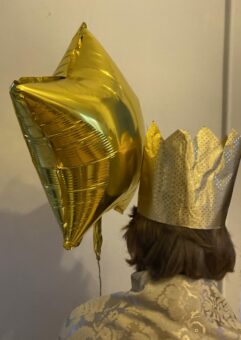 Ein goldener Luftballonstern, eine goldene Krone und der wuschelige Hinterkopf von Junior