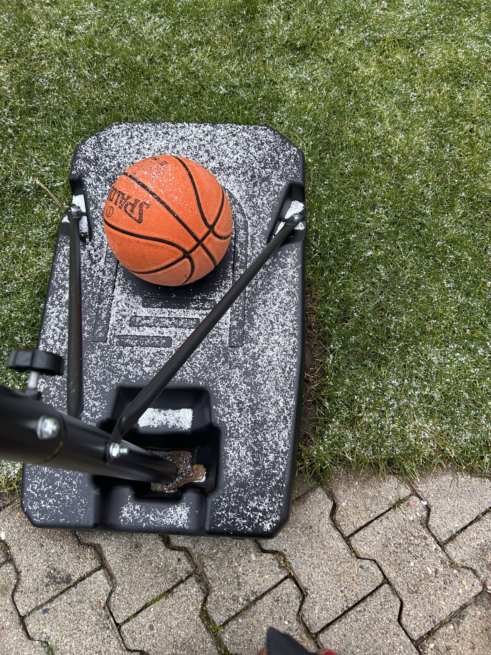 Ein Basketball liegt auf einem Baskeltballkorb mit Schnee