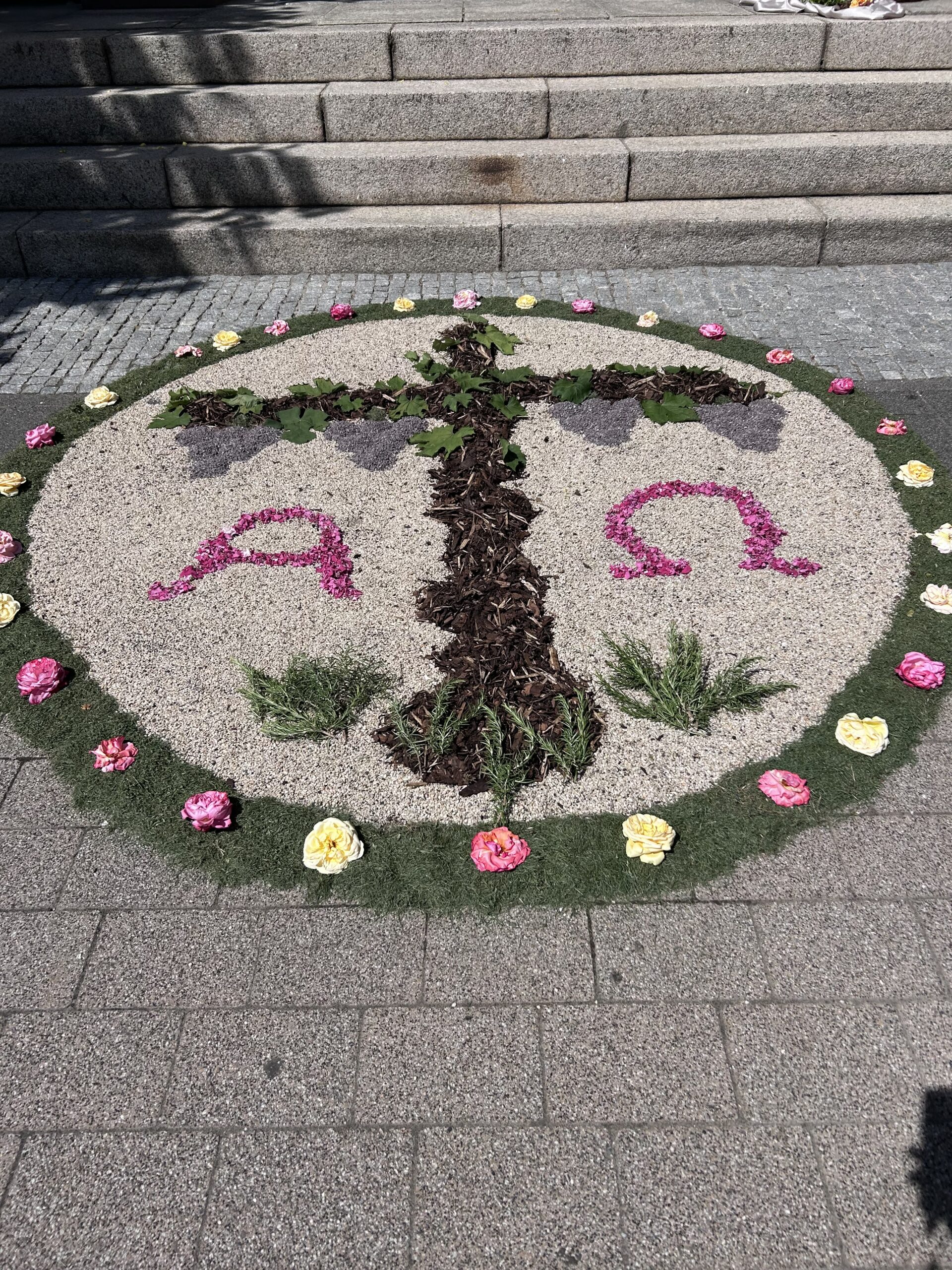 Ein Blütenteppich mit einem Kreuz aus Blumen gelegt